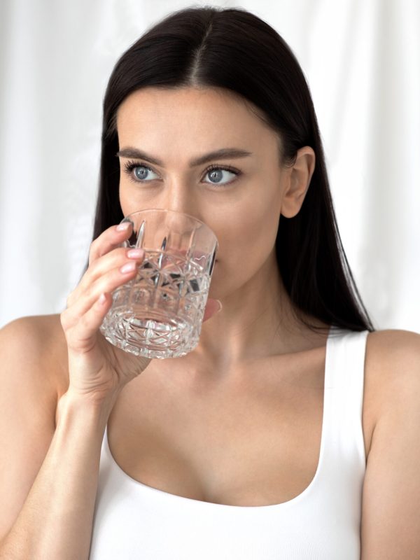 Diet, proper nutrition and taking care of beauty and health at home at morning. Millennial european pretty female drinks clear water from glass, on white background, free space, close up